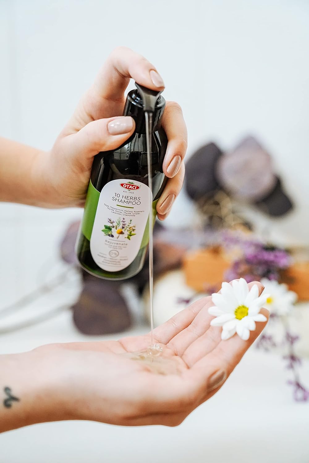 A visual of Otaci 10 Herbs Shampoo rejuvenating natural ingredients. Pumping shampoo into hand.