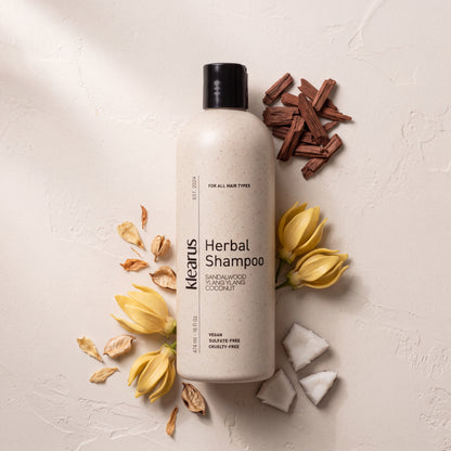 Klearus All Hair Types herbal shampoo flat-lay with sandalwood chips, ylang ylang blossoms and halved coconut